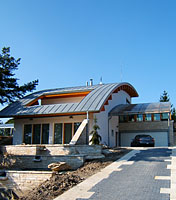 Strohá architektura domu je založena na kubickém objemu s okenními otvory krytém zakřivenou přečnívající střechou. Střecha podobného tvaru kryje zimní